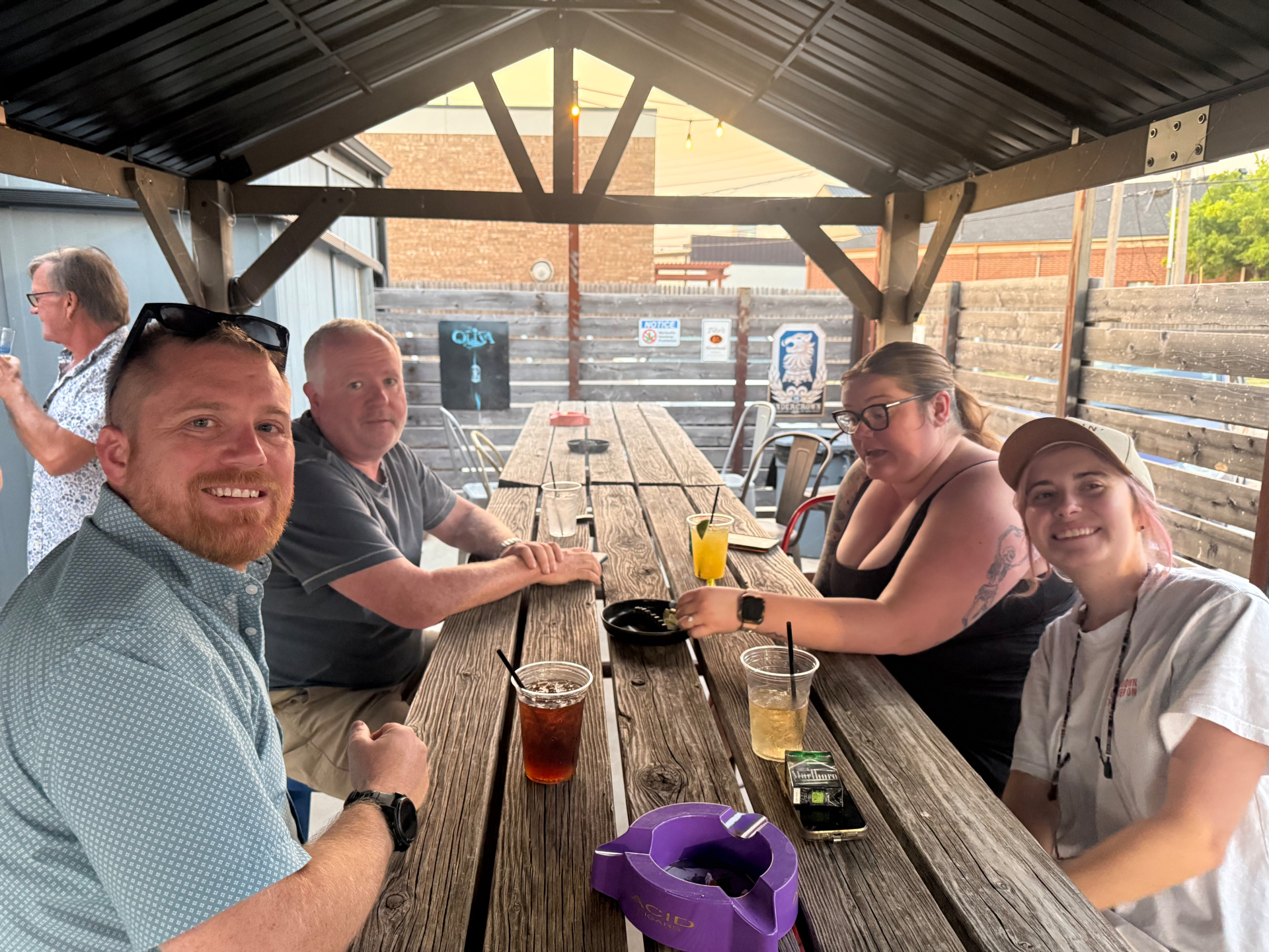 Regulars sharing drinks and laughs under the covered patio at The Wilshire